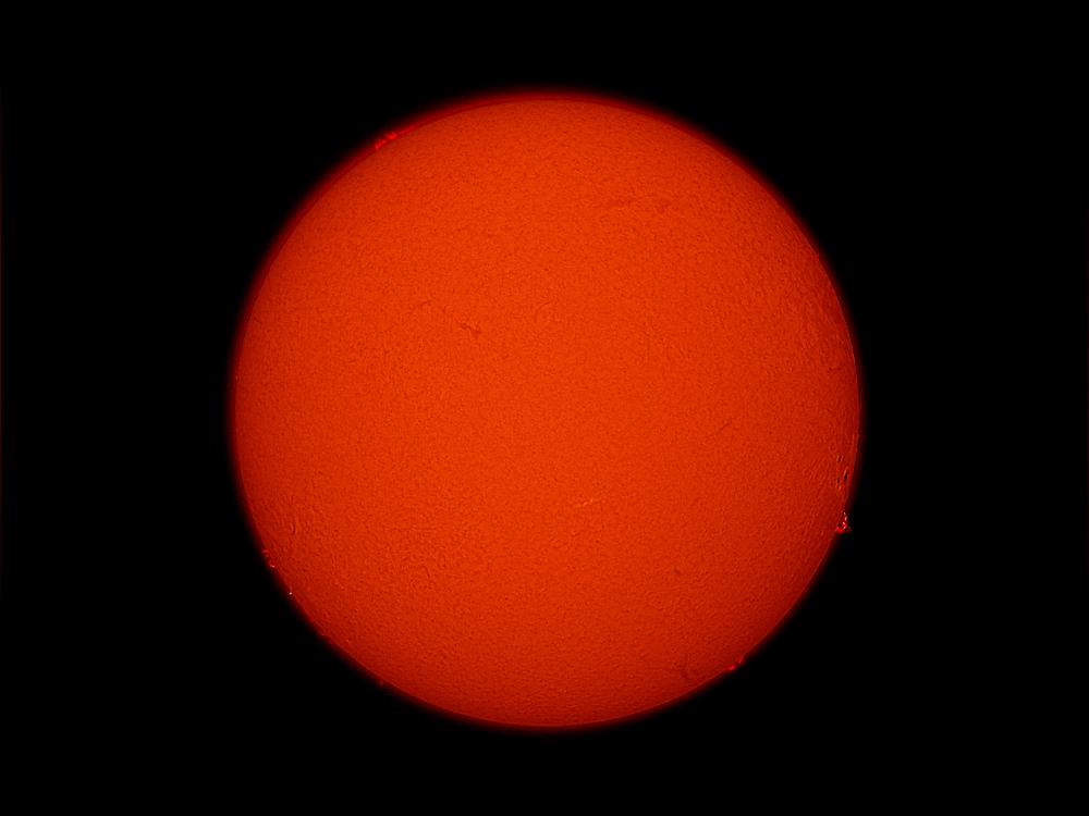 Disk view of the Sun's atmosphere with the remnants of a sunspot cluster visible as phages (lighter colored clouds) on the far bottom right side of the disk.