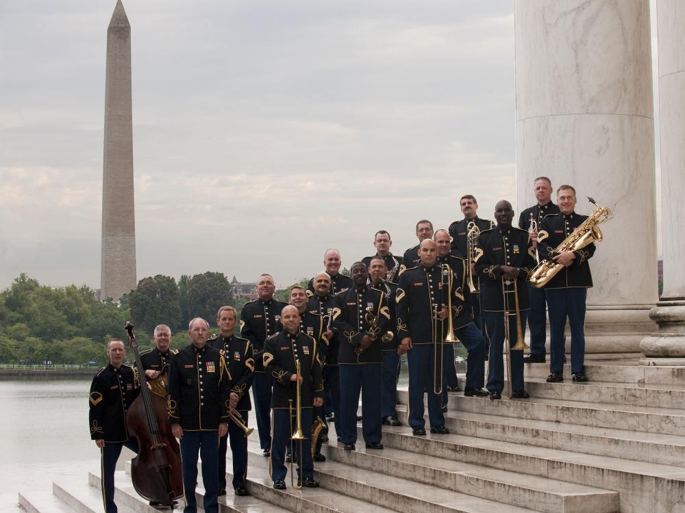 A group of U.S. Army musicians stand with their instruments on a set of stairs.