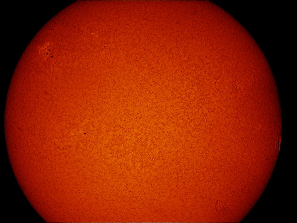 Partial disc view of the Sun's atmosphere. A sunspot cluster is visible on the upper left quadrant of the disk.