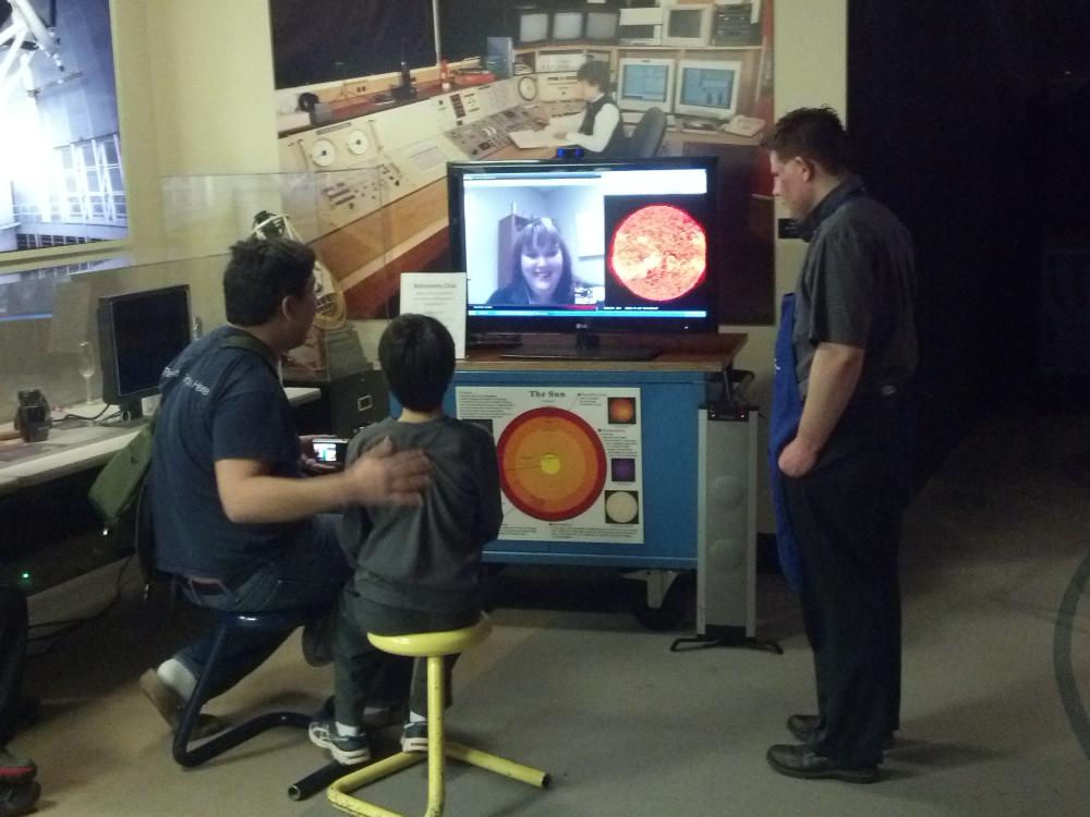 Four museum visitors video chat with a museum expert on astronomy inside the Museum's observatory.