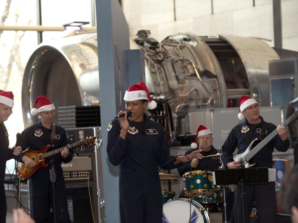 A group of U.S. Air Force musicians perform at the Museum. They are wearing red and white Santa hats.