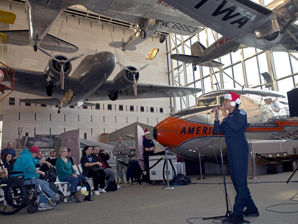 A musician from the U.S. Air Force performs as part of a band at the Museum. They are wearing a red and white Santa hat.