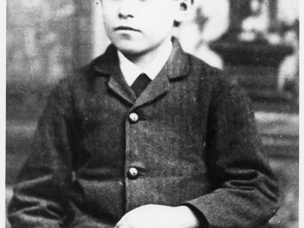 Black and white portrait of a boy sitting in a chair.