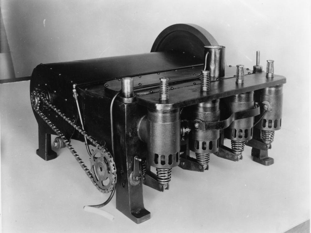 A dark colored box-shaped engine with four cast iron cylinders and an aluminum case.