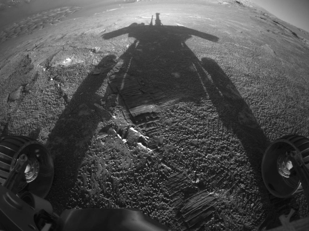 A shadow reflects from a Rover, a travelling robot, in afternoon sunlight on Mars.