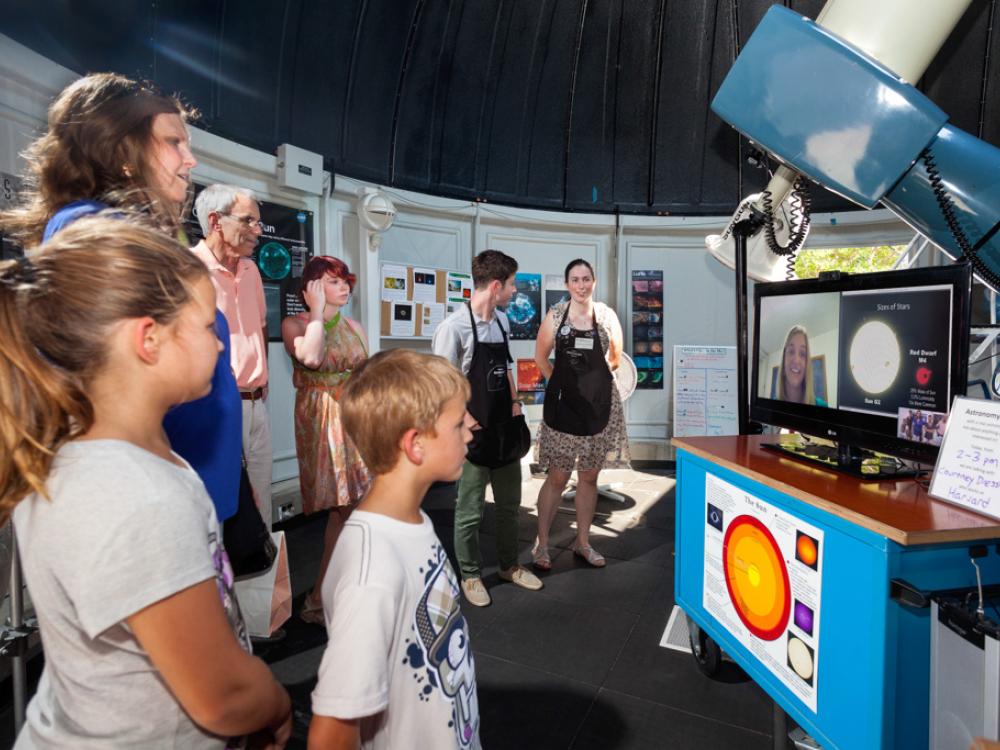 Museum visitors video chat with an expert on astronomy inside the Museum's observatory.