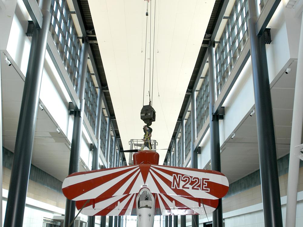 A red and white biplane is lifted into its display position above visitors at the Museum's Steven F. Udvar-Hazy Center.