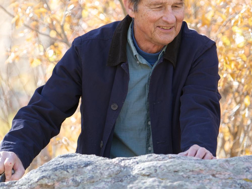 Karl G. Hufbauer, a man, stands outside behind a rock.