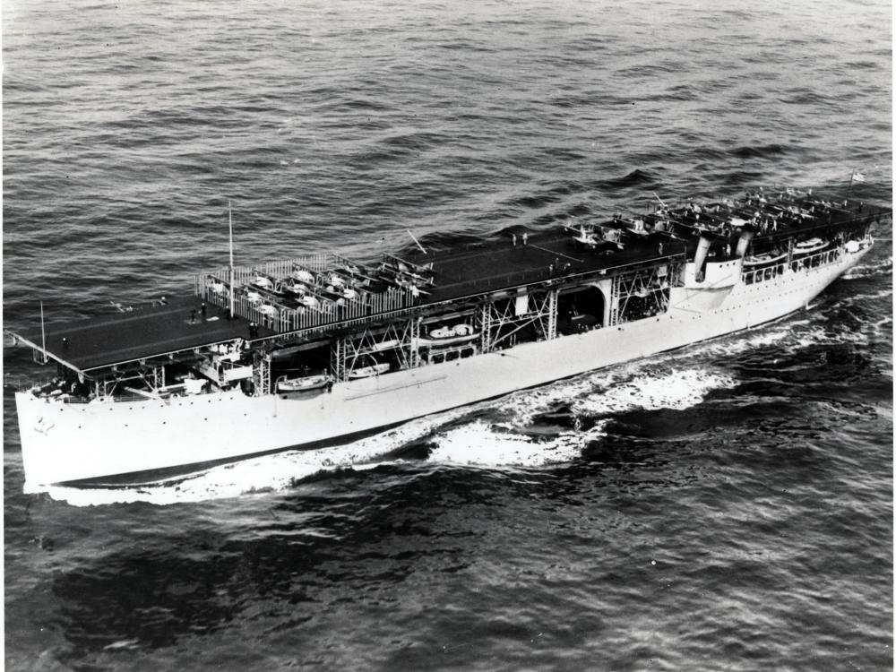 Side view of the first American aircraft carrier, a large boat that carried aircraft, in an ocean.