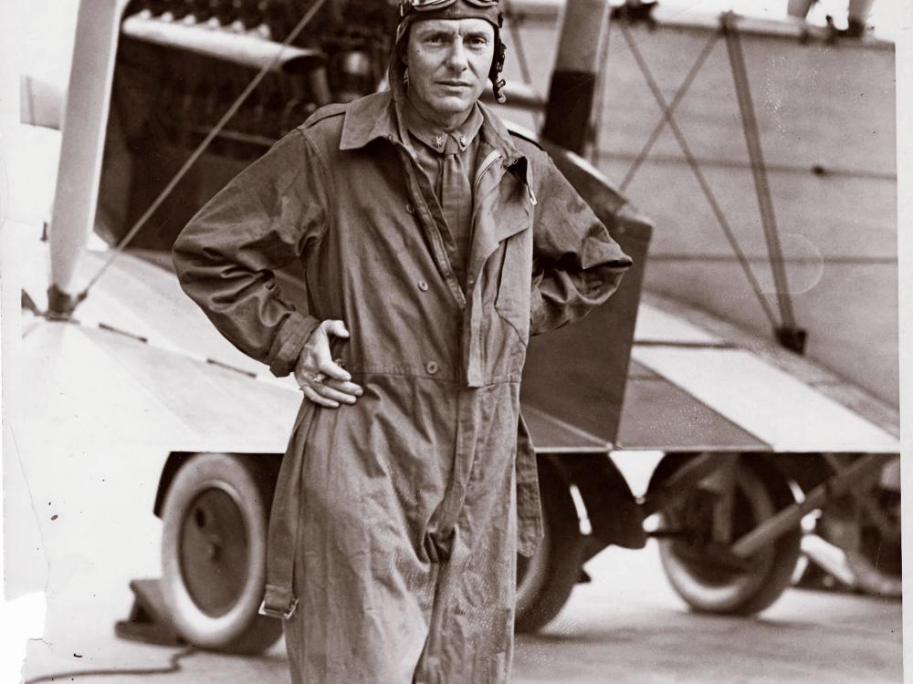 Ross Rowell, a white male pilot, poses for a portrait wearing aviator gear.