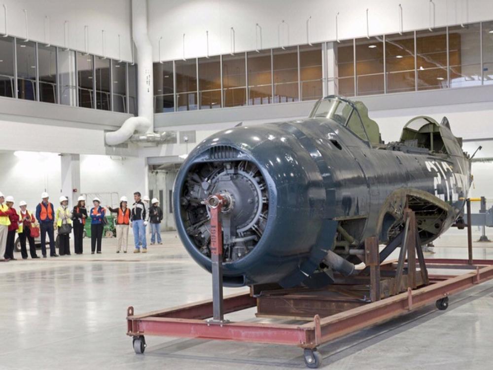 The fuselage of a blue military monoplane is the only aircraft inside the museum's restoration hangar.