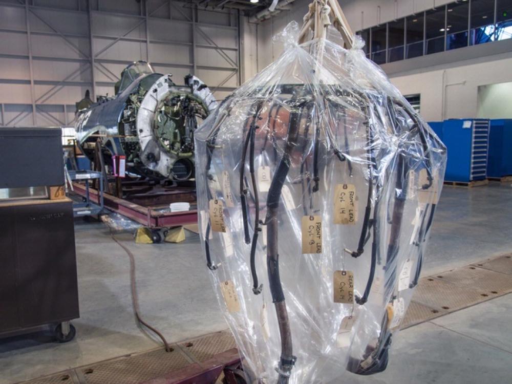 A part of the ignition system of a military aircraft is hanging above the ground in a plastic layer.