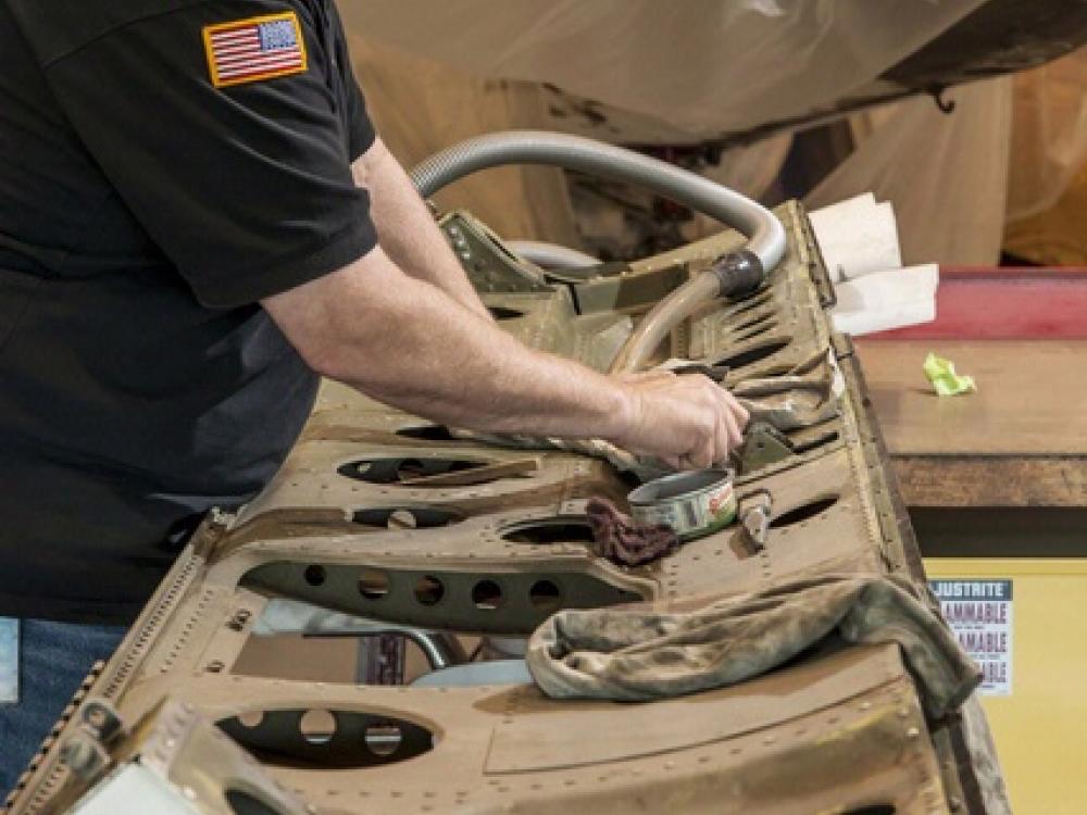 A museum specialist works on cleaning a door of a military monoplane.