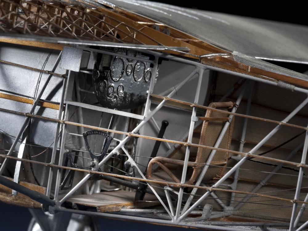 Close-up view of the interior of a cutaway model of the Spirit of St. Louis, a silver-colored monoplane with wooden and metal parts.