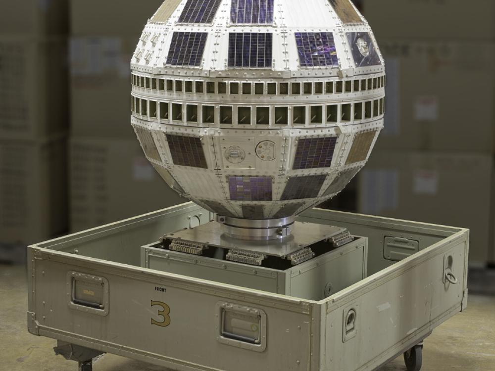 A small sphere-shaped satellite with an orange, cylindrical prism top.