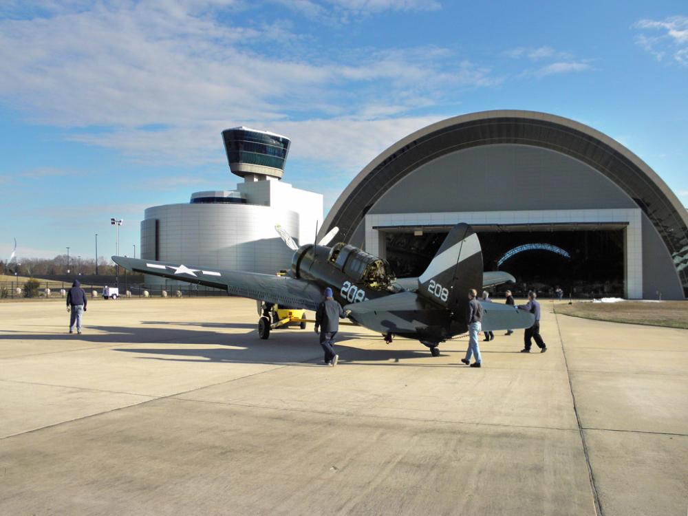 A group museum specialists work to move a gray and black monoplane into its permanent display spot inside the Museum's Steven F. Udvar-Hazy Center.