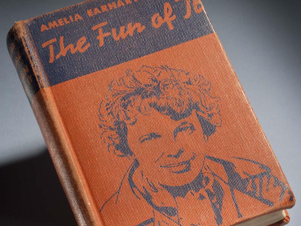 Orange and black book cover featuring a drawing of Amelia Earhart. The book is titled "The Fun of It" and is written by Amelia Earhart.