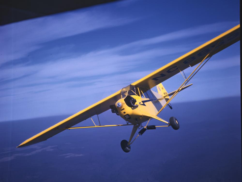 Front view of a yellow monoplane with one engine. The monoplane is in flight.