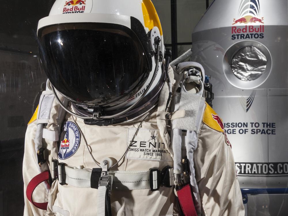 Close up of a high-altitude pressure suit used in a free-fall mission sponsored by Red Bull. The suit is a light-brown color and contains multiple tubes for life support. The helmet features a black sun visor.