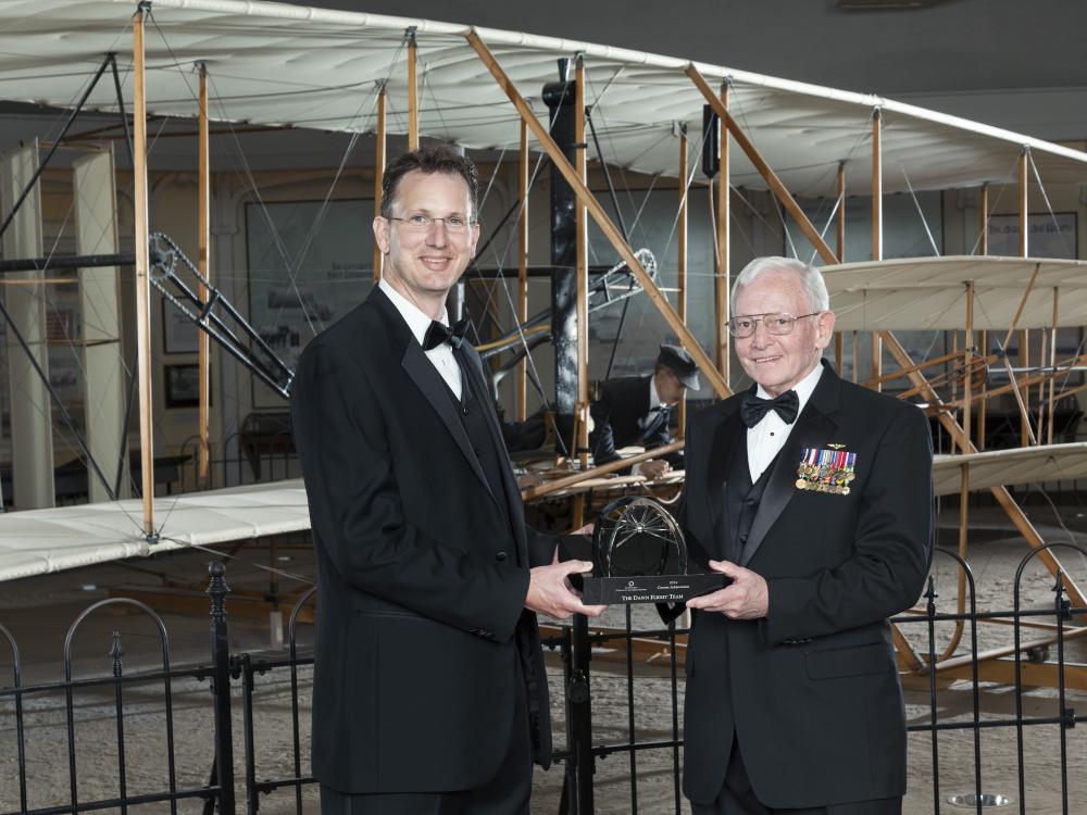 Two white men hold a trophy which was presented at the Museum.