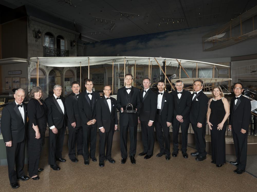 A group of individuals stand together with a trophy at an event hosted by the Museum.