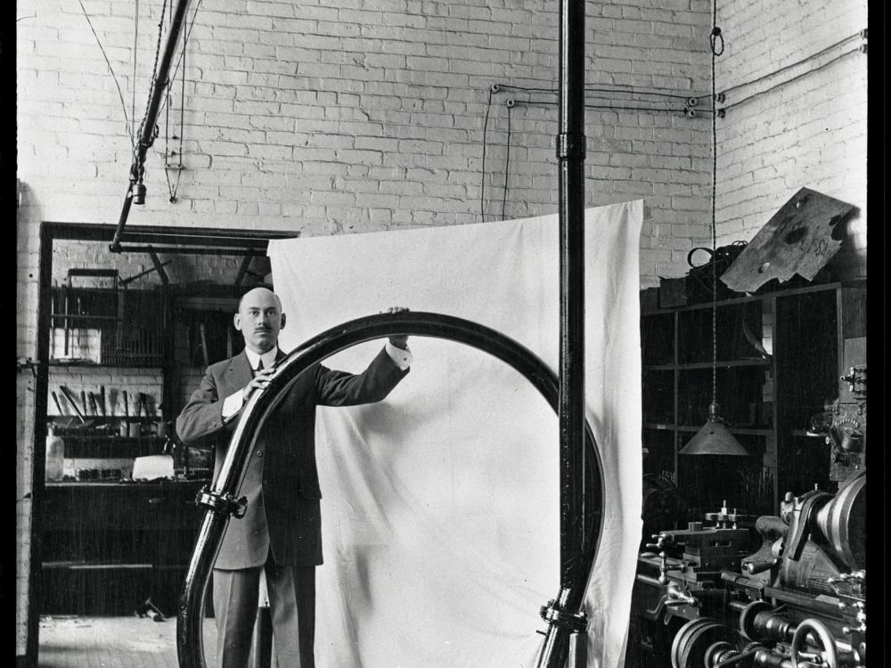 A white man stands while holding a large rounded tube.