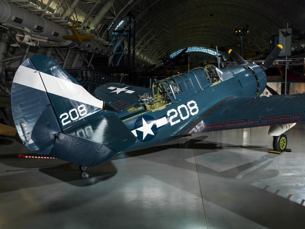 Dark blue and white military monoplane on display at the Museum. Monoplane has one engine. The number 208 is painte on the side and back fin of the plane.