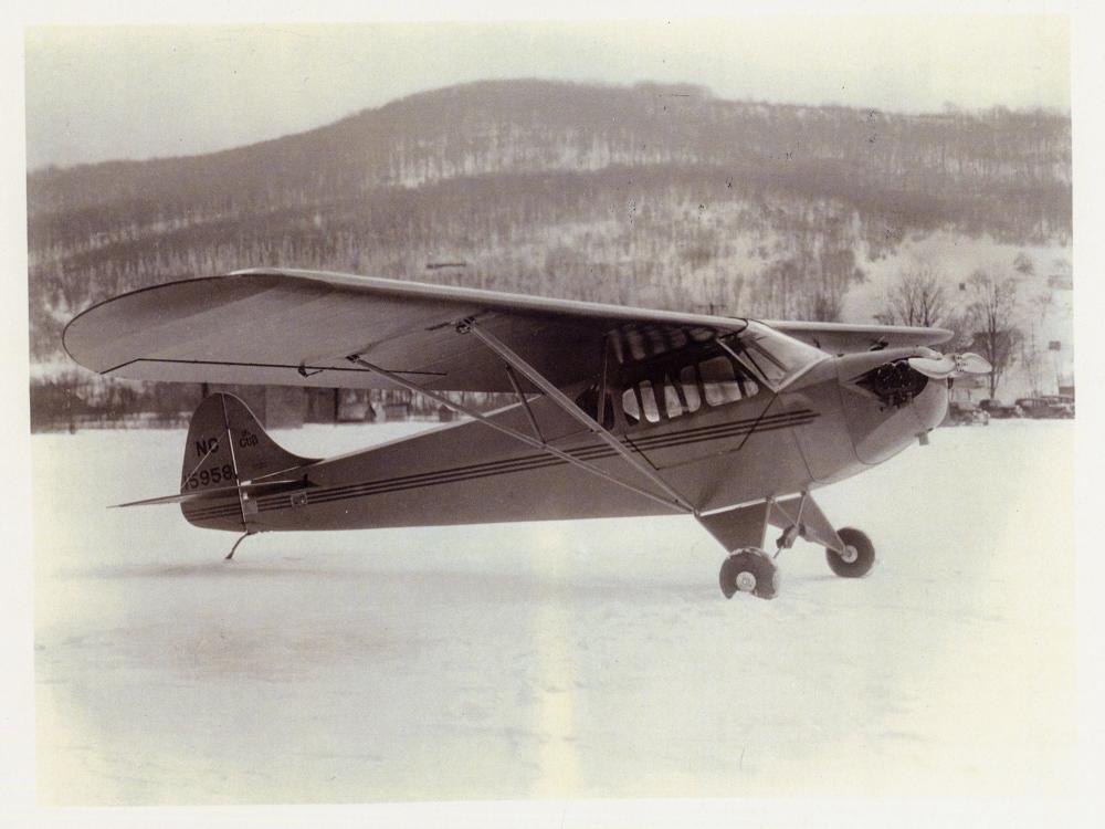 Side view of light-colored monoplane with one engine on ground.