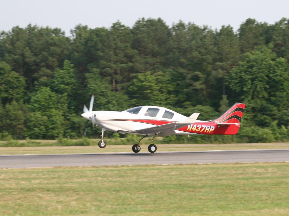 Side view of white and red monoplane with one engine. Monoplane is in takeoff position. Registration number "N437RP" painted in white near tail of plane.