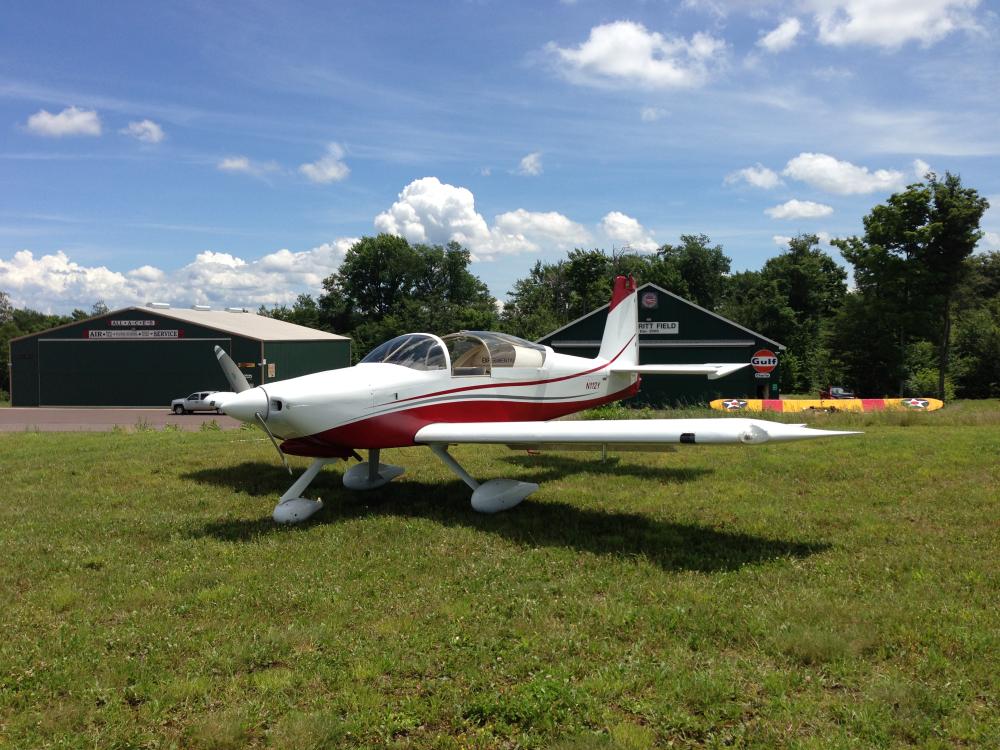 Side view of white and red monoplane with one engine and fixed landing gear.