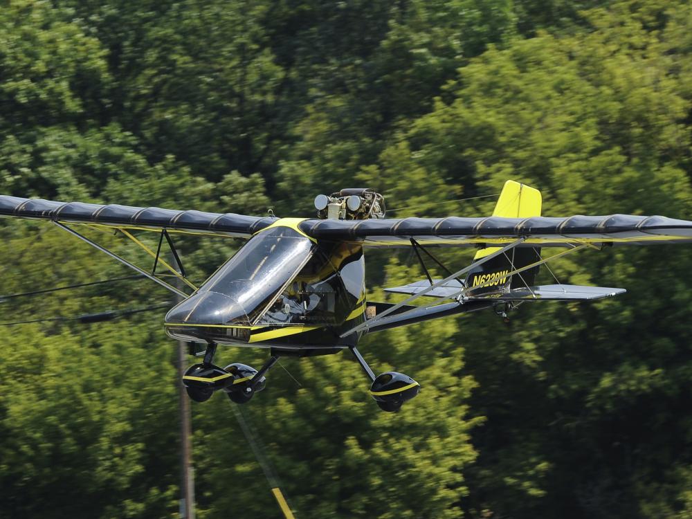 Side view of a black monoplane in flight. Monoplane has fixed landing gear.