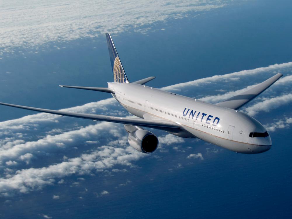 A Boeing 777 commercial jet with white, blue, and yellow United Airlines livery.