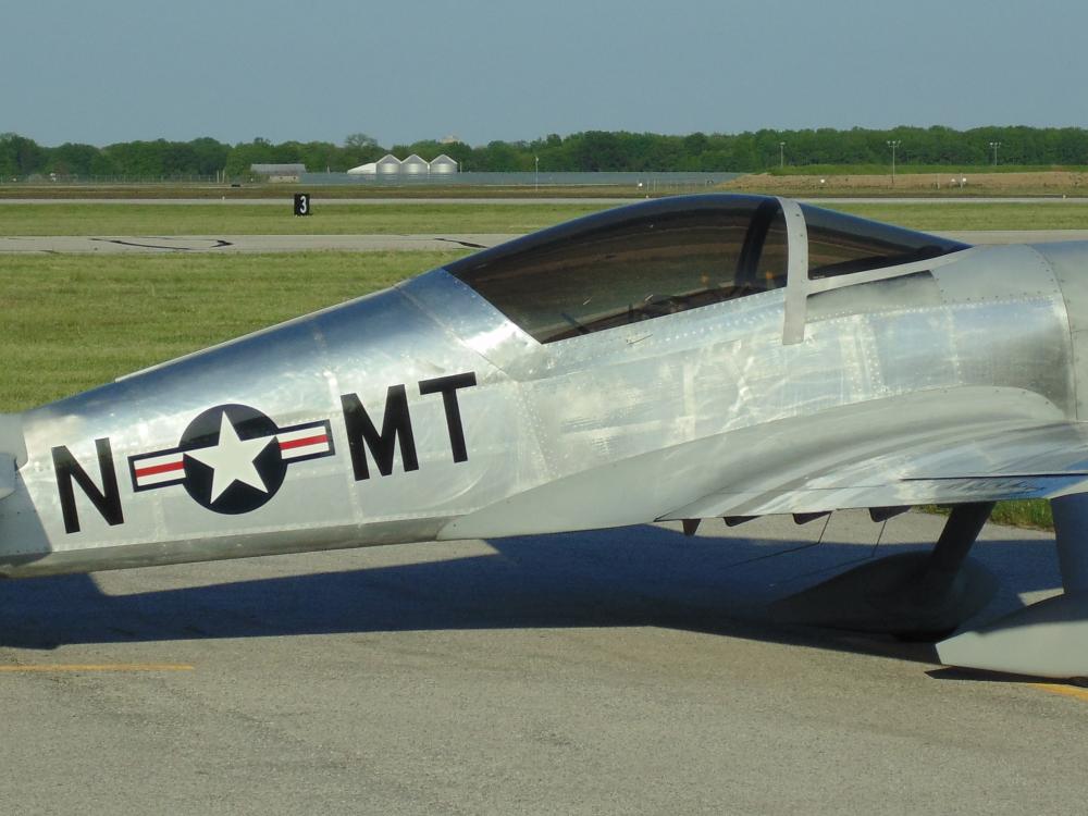 Side view of silver monoplane with one engine and fixed landing gear.