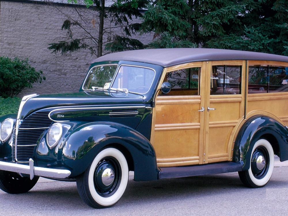 Side view of dark-colored metal, four-door automobile with wooden sides.