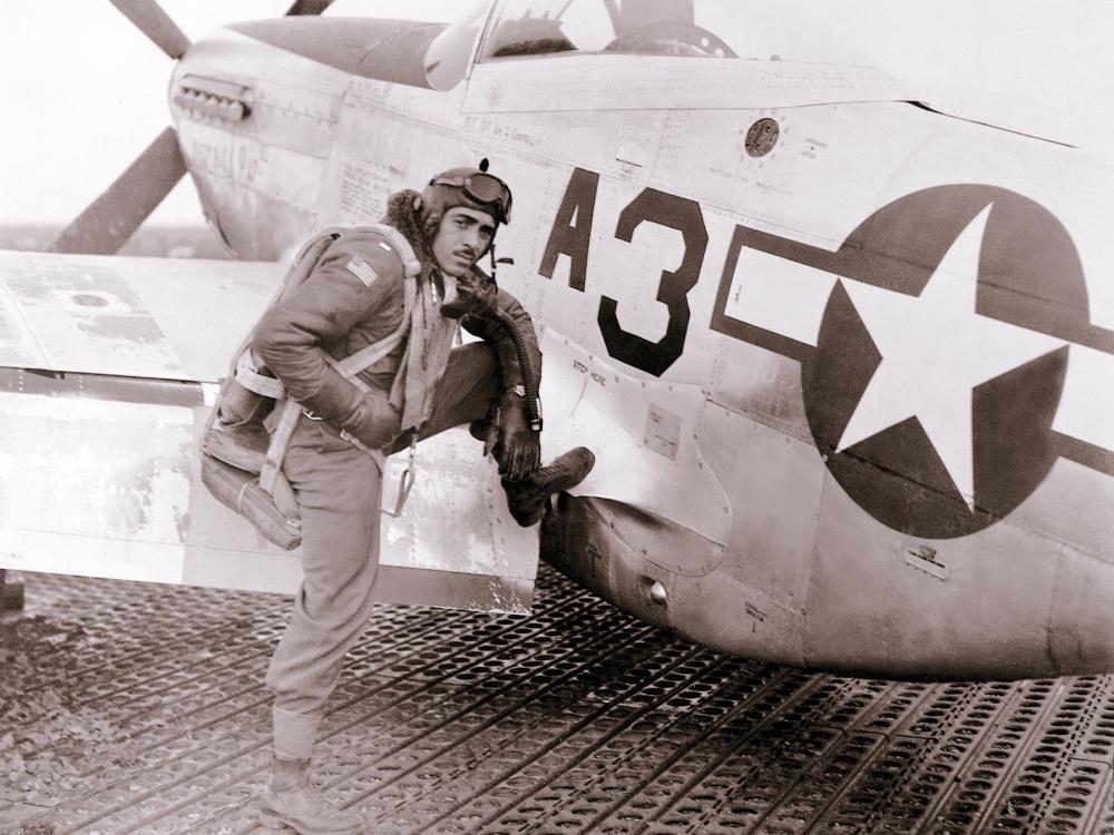 Lt. Edward M. Thomas, an African-American Tuskegee Airman, sits on the wing of an aircraft.