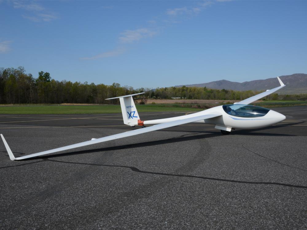 Side view of white glider aircraft with notably long wings.