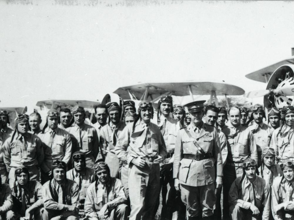 A large group of Marine Corps pilots in the early 1930s stand together outdoors for a portrait.