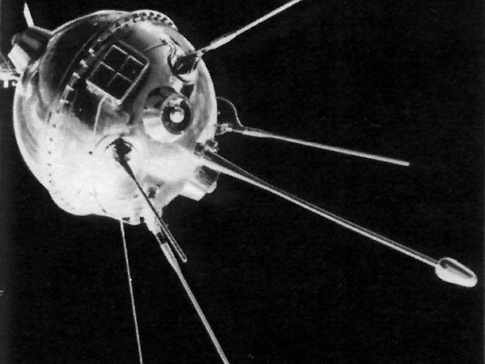 View of metal orbiting sphere-like base of an object with multiple antenna probes attached to bottom of base object. A square attachement featuring smaller square panels is attached above the antennae probes.