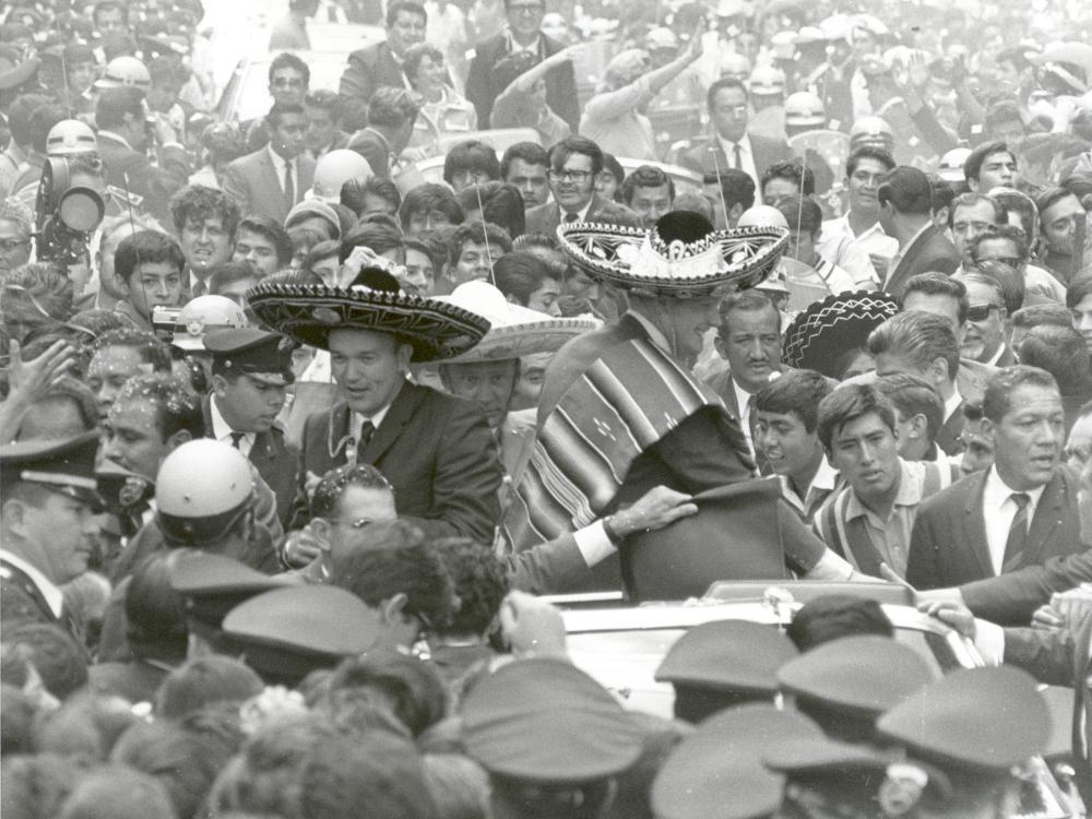 The three Apollo 11 astronauts (Neil Armstrong, Edwin "Buzz" Aldrin, Jr., and Michael Collins) are wearing sombreros and ponchos. They are surrounded by thousands of people in Mexico City, Mexico.