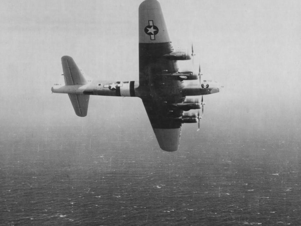 View of a U.S. military monoplane during a test flight over an ocean.