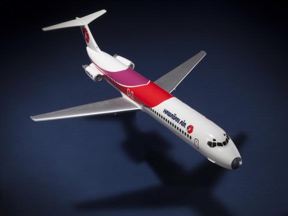 Top view of resin commercial aircraft model with white, red, and purple livery. Hawaiian Air is painted toward the front of the fuselage.