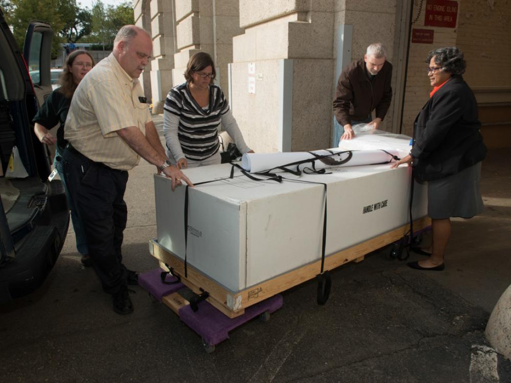 Five Museum staff members transport Neil Armstrong's spacesuit outside into another Smithsonian museum building.