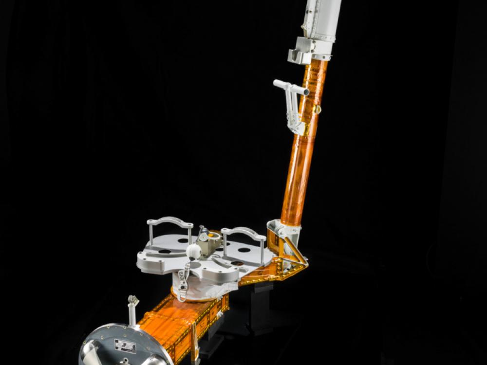 Orange and silver-colored L-shaped object with two restraints meant to hold a single foot during a spacewalk. On both ends, there is a single attachment site.