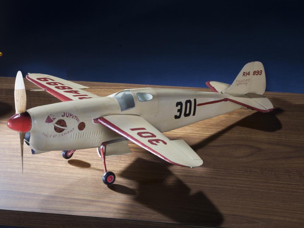 Side view of white monoplane model with one engine. The number 301 is painted in black on the rear of the fuselage and in red on the left wing.