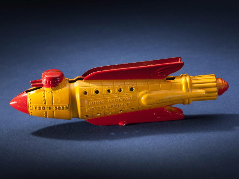 Side view of yellow rocket with red fins and nose.