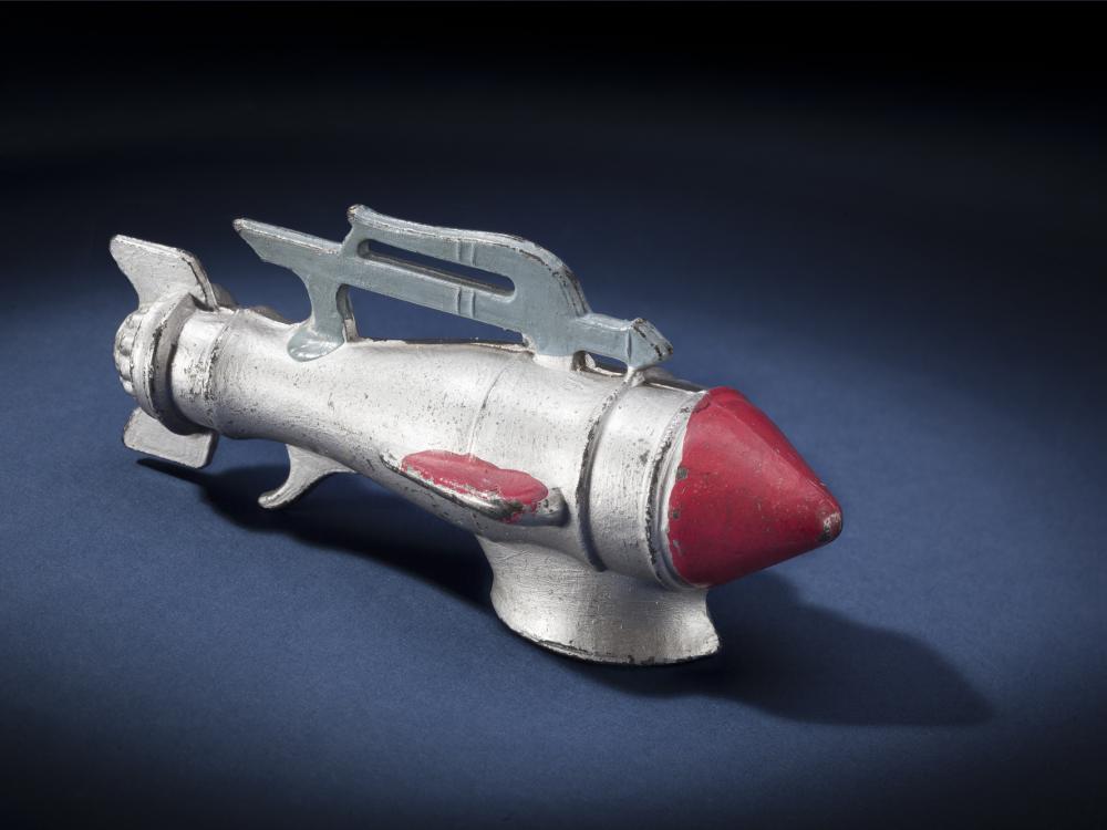 Side view of silver-colored metal missile-shaped spaceship with red nose.