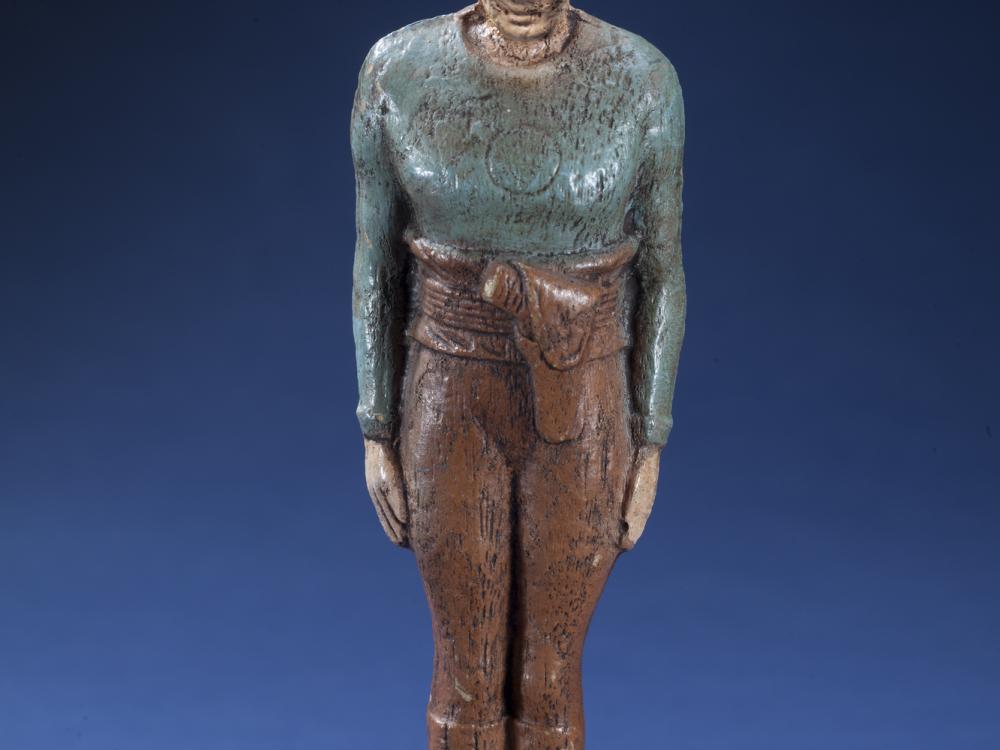 Front view of person-shaped statuette with blue-gray top and brown pants. "Flash Gordon" is painted in black on the front of the base.