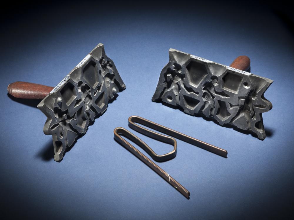 Set with two separate molds and a metal clamp. Molds have a brown-colored wooden handle on the back.