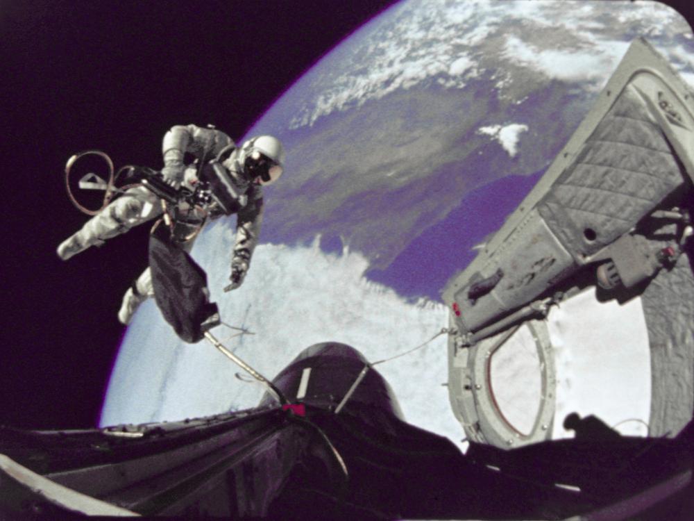 Edward White, a male astronaut, performs a spacewalk while tethered to the Gemini 4 spacecraft.