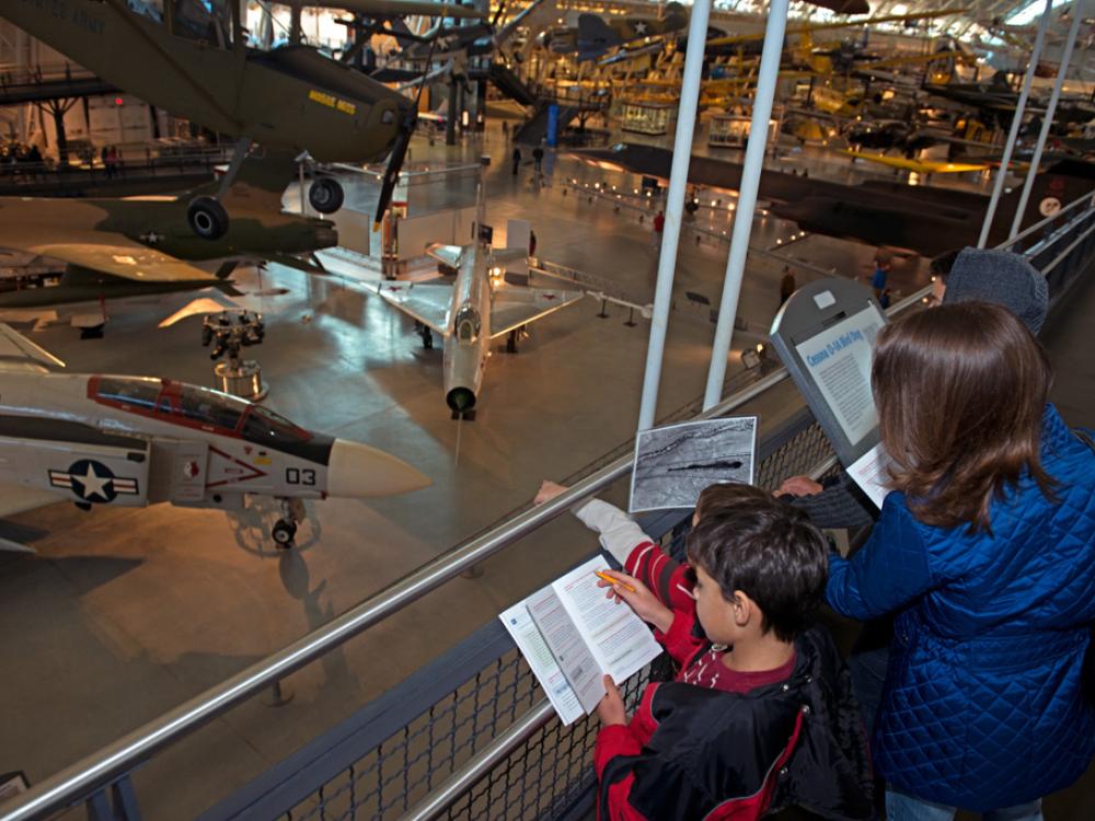 Three younger Museum guests observe objects in the Museum while playing a Museum-sanctioned alternate reality game.